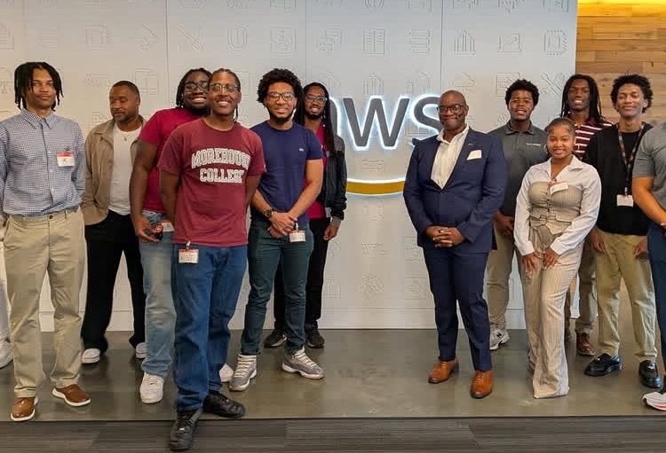 AARI students and staff in front of the AWS logo during a site visit